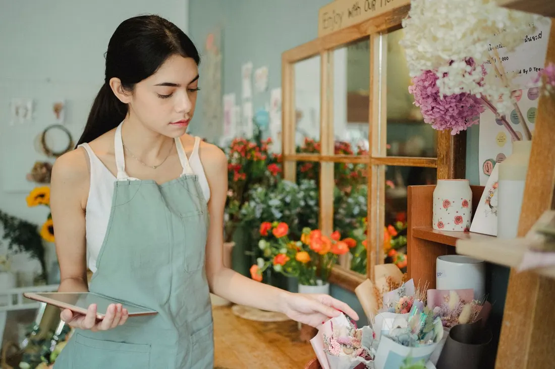 A florist checking an order on a tablet in her flower shop